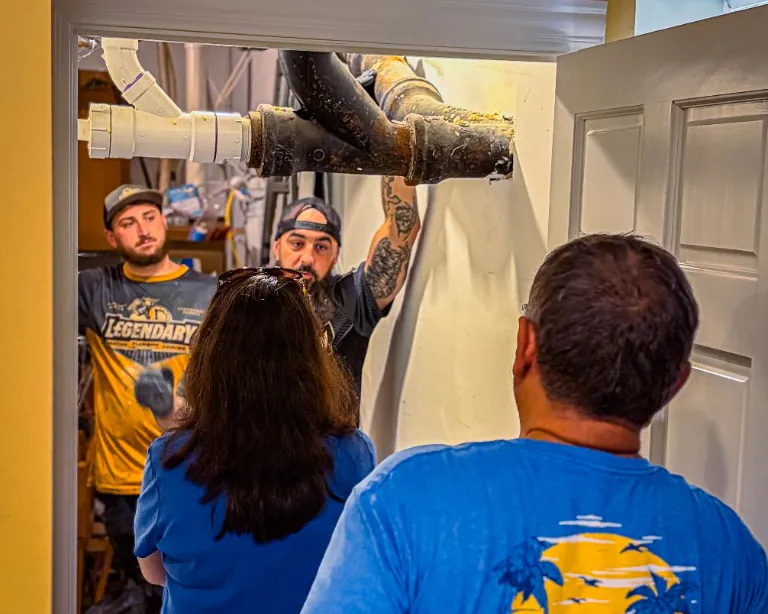Legendary Service technicians showing homeowners the overhead drain line during a service call